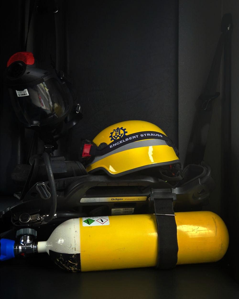 Helm pemadam kebakaran kuning, masker wajah penuh, dan tabung SCBA yang disimpan siap pakai