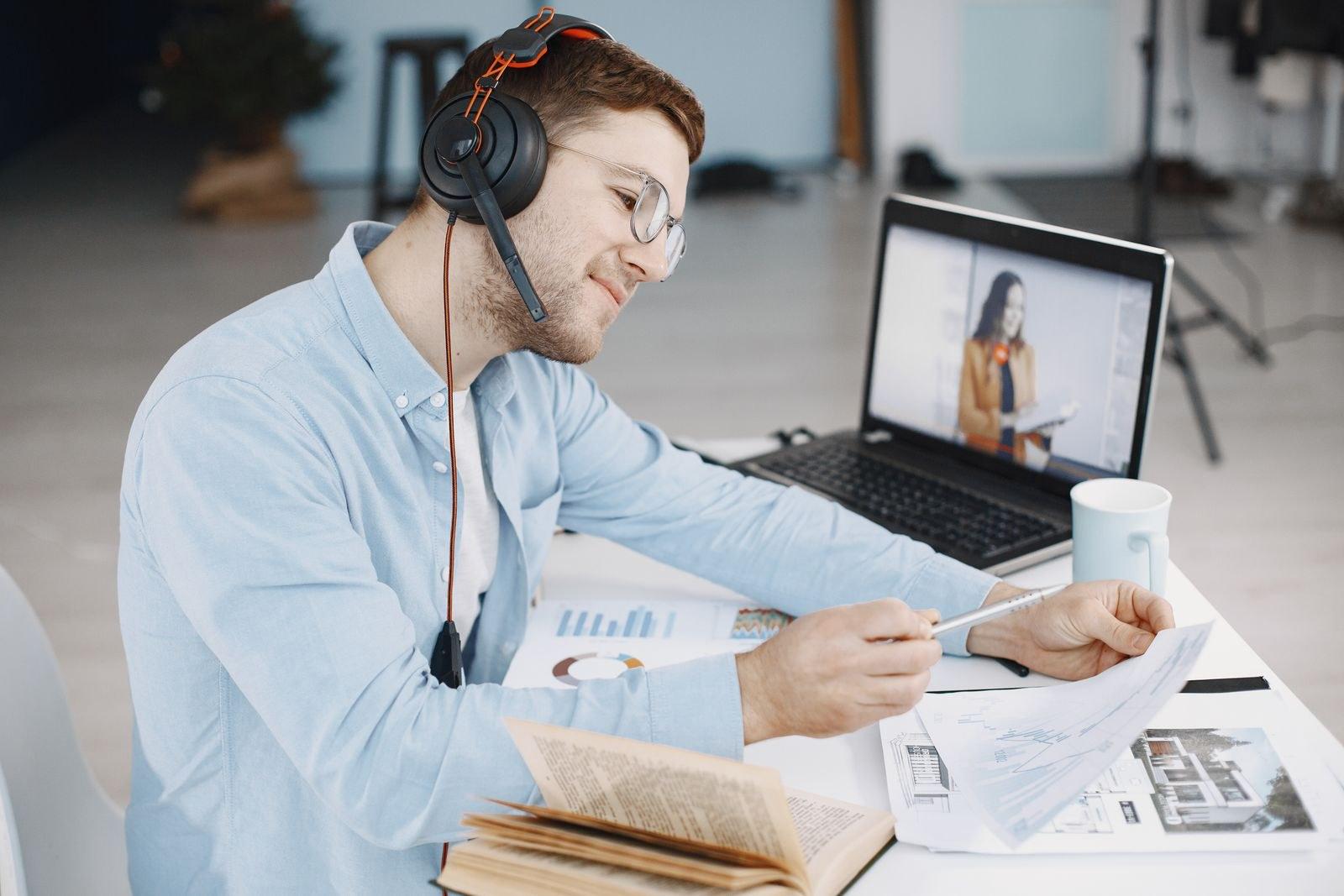 Peserta kelas daring memakai headset mencatat materi di meja kerja