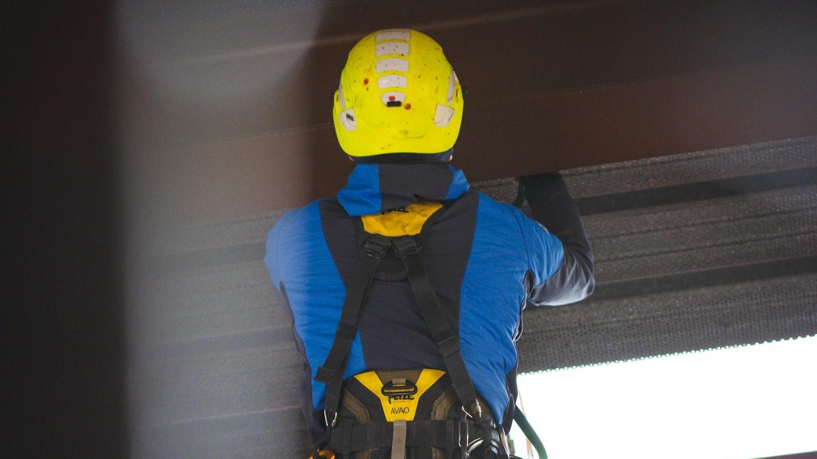 Pekerja memakai helm dan full body harness saat bersiap bekerja di ketinggian